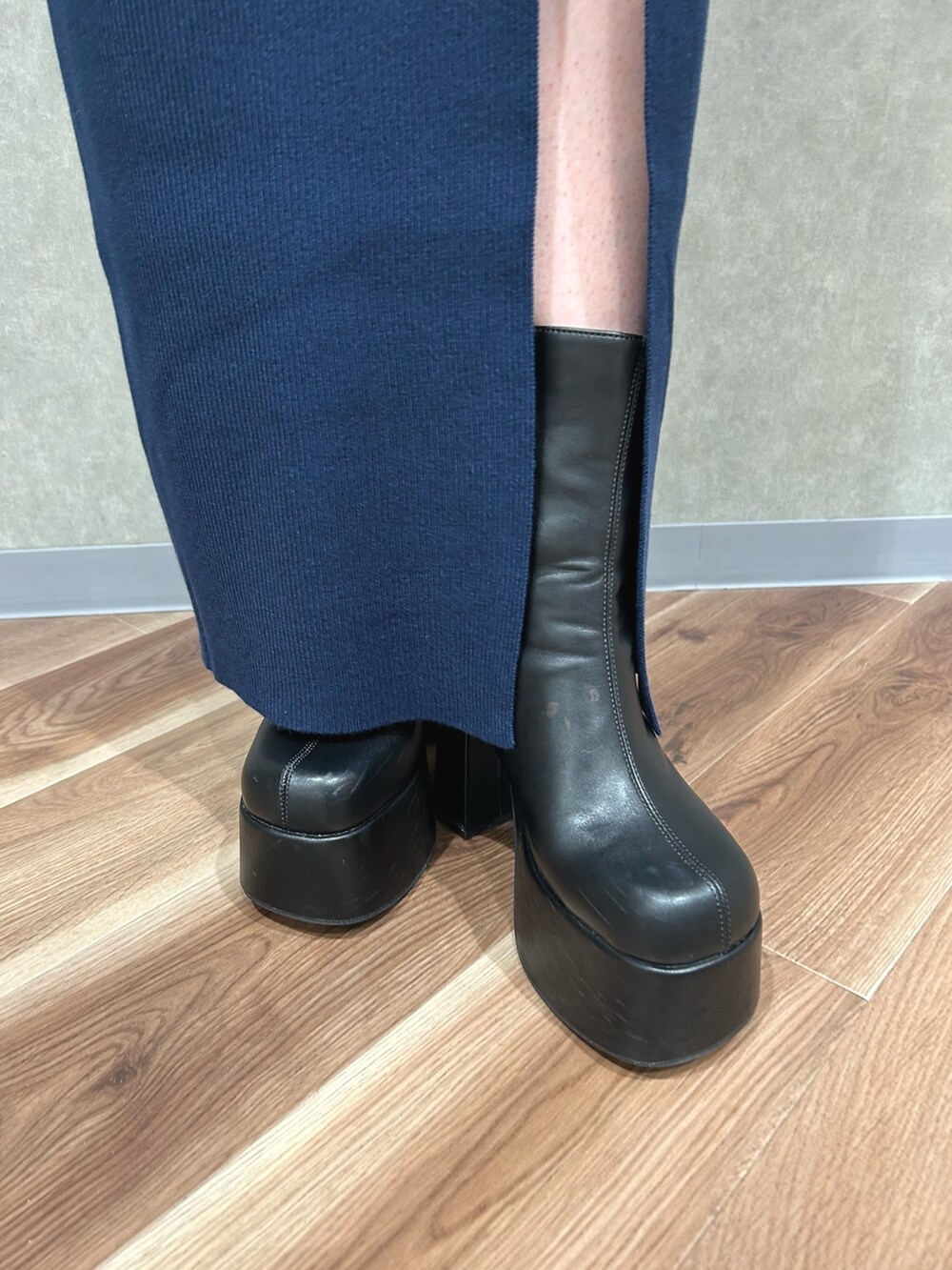 ブラック系のダウンベスト、ブルー系のワンピース、ブラック系のブーツを着用したレディースの秋コーディネートの6枚目の写真