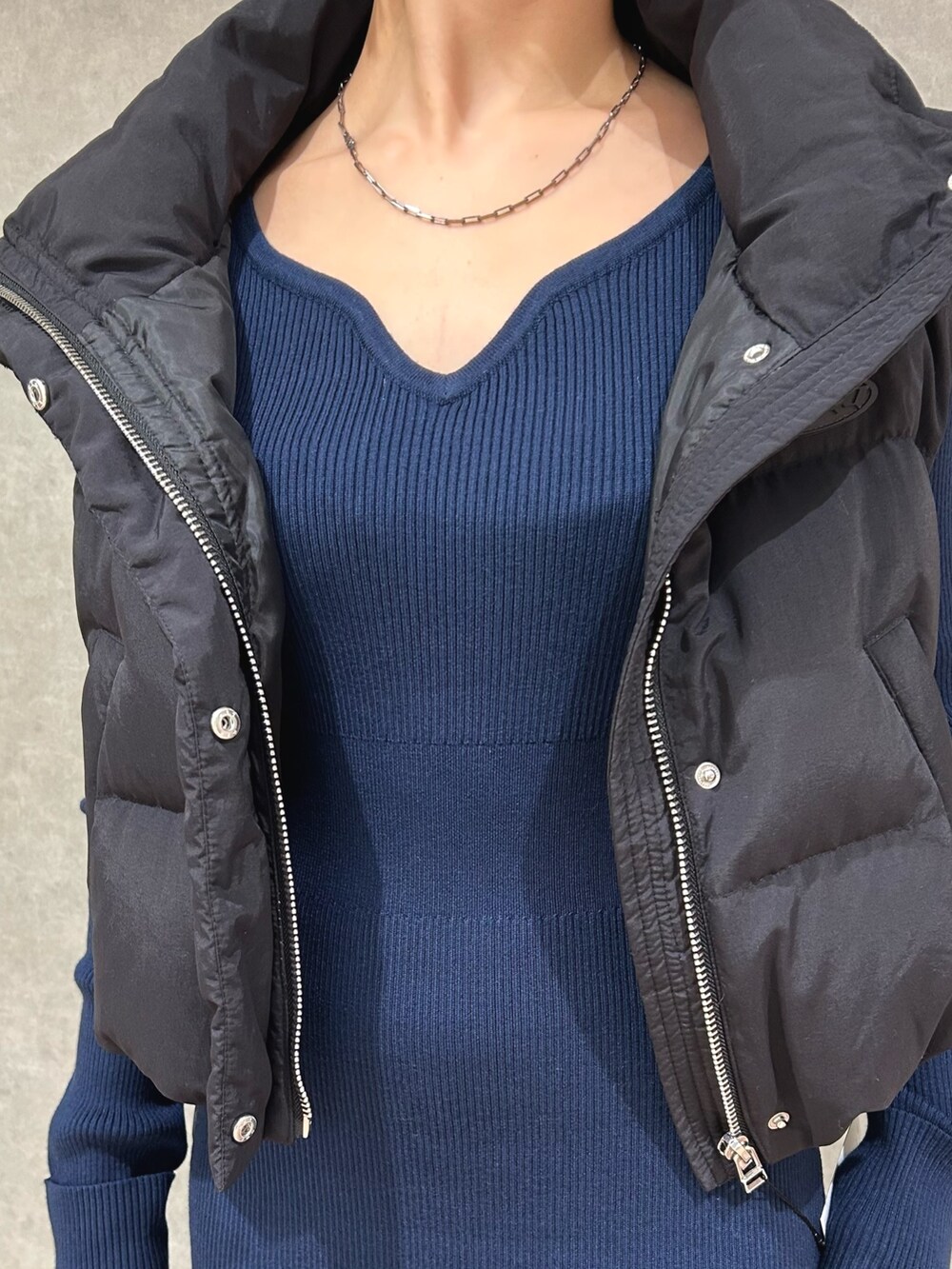 ブラック系のダウンベスト、ブルー系のワンピース、ブラック系のブーツを着用したレディースの秋コーディネートの5枚目の写真