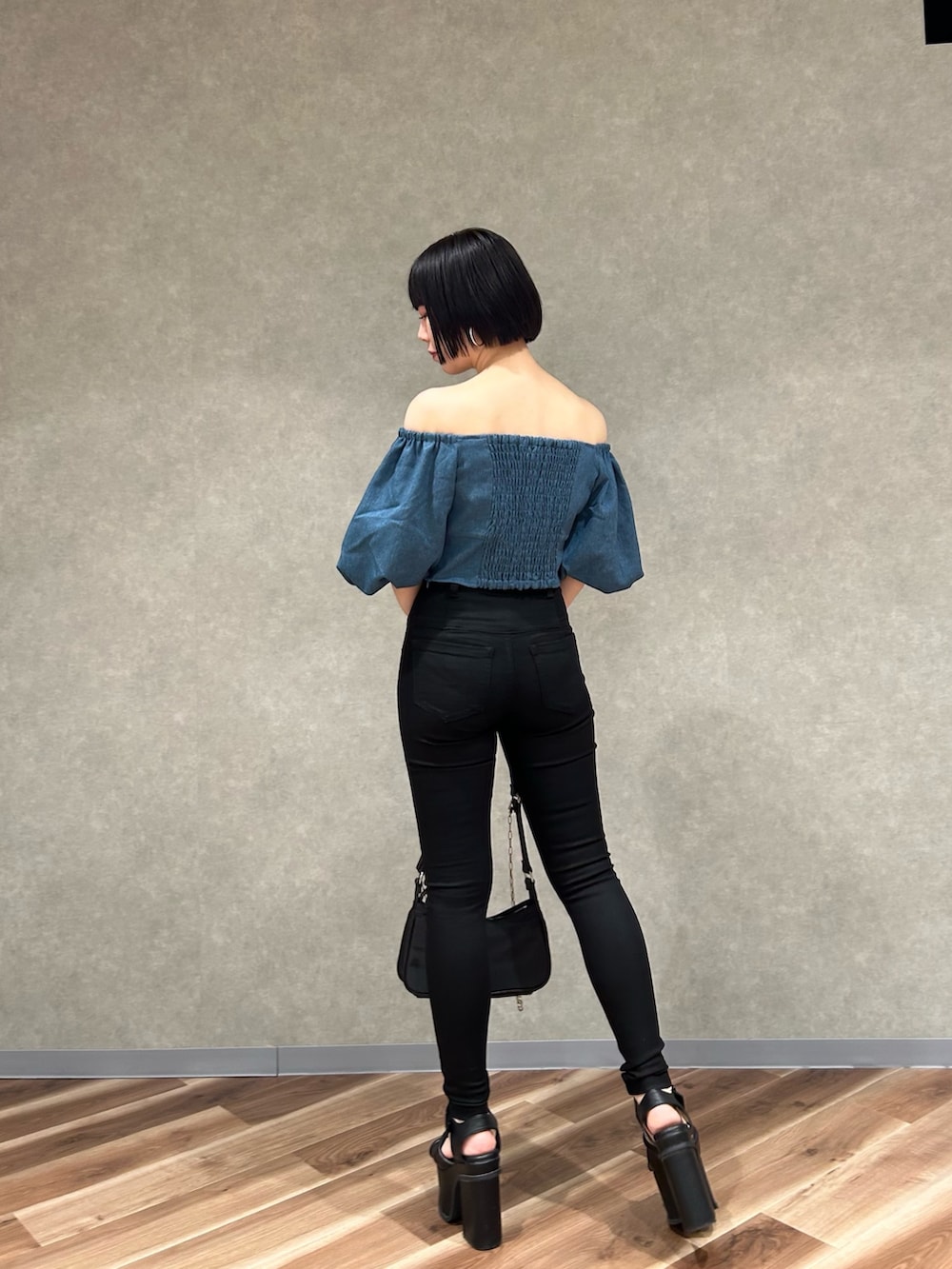 ブラック系のデニムパンツ、ブルー系のTシャツ/カットソー、ブラック系のハンドバッグを着用したレディースの夏コーディネートの4枚目の写真