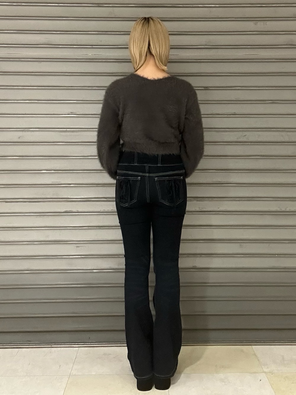 グレー系のニット/セーター、グレー系のTシャツ/カットソー、ブルー系のデニムパンツを着用したレディースの秋コーディネートの3枚目の写真