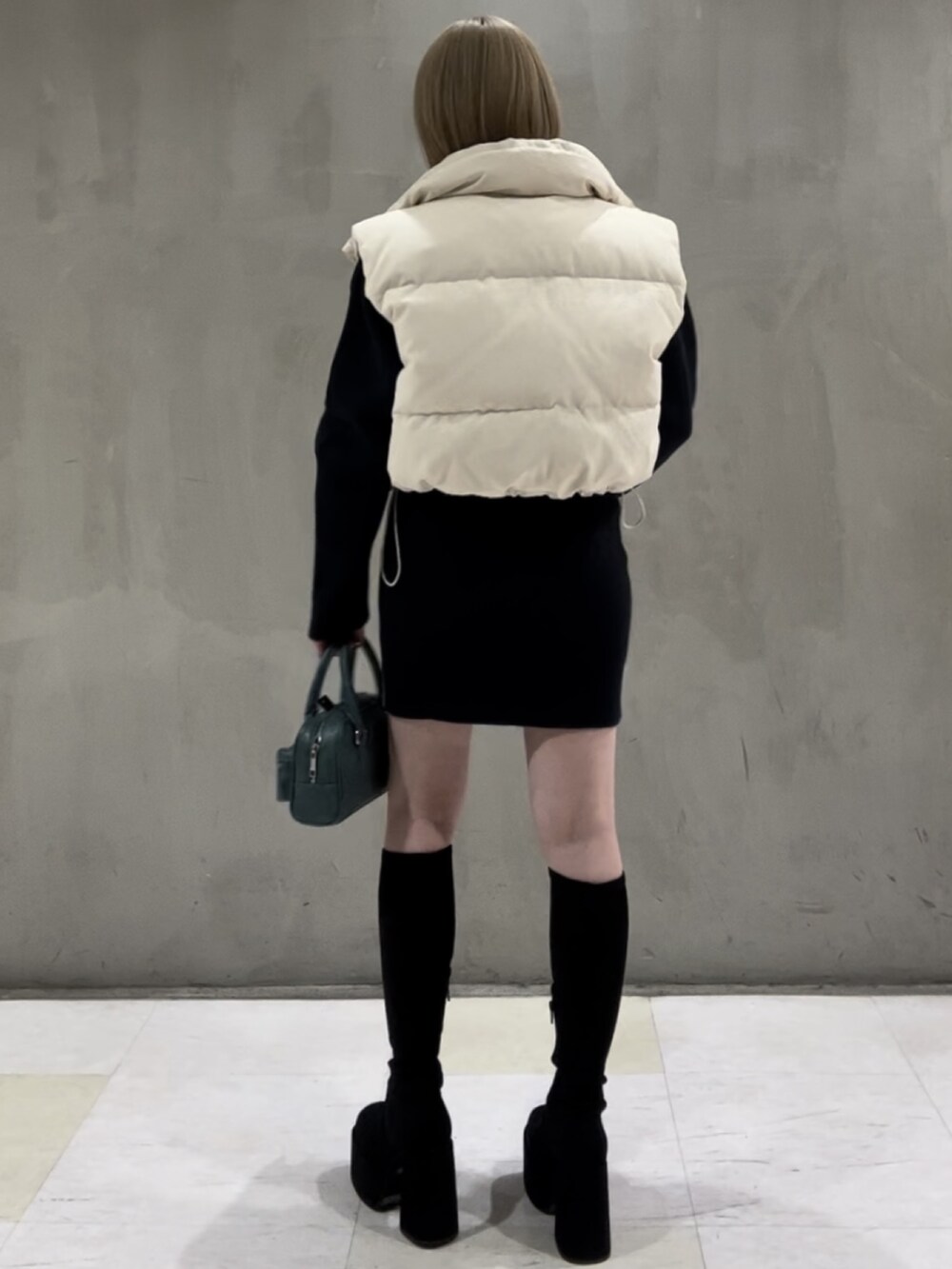 ホワイト系のダウンベスト、ブルー系のニット/セーター、ブルー系のスカートを着用したレディースの秋コーディネートの3枚目の写真