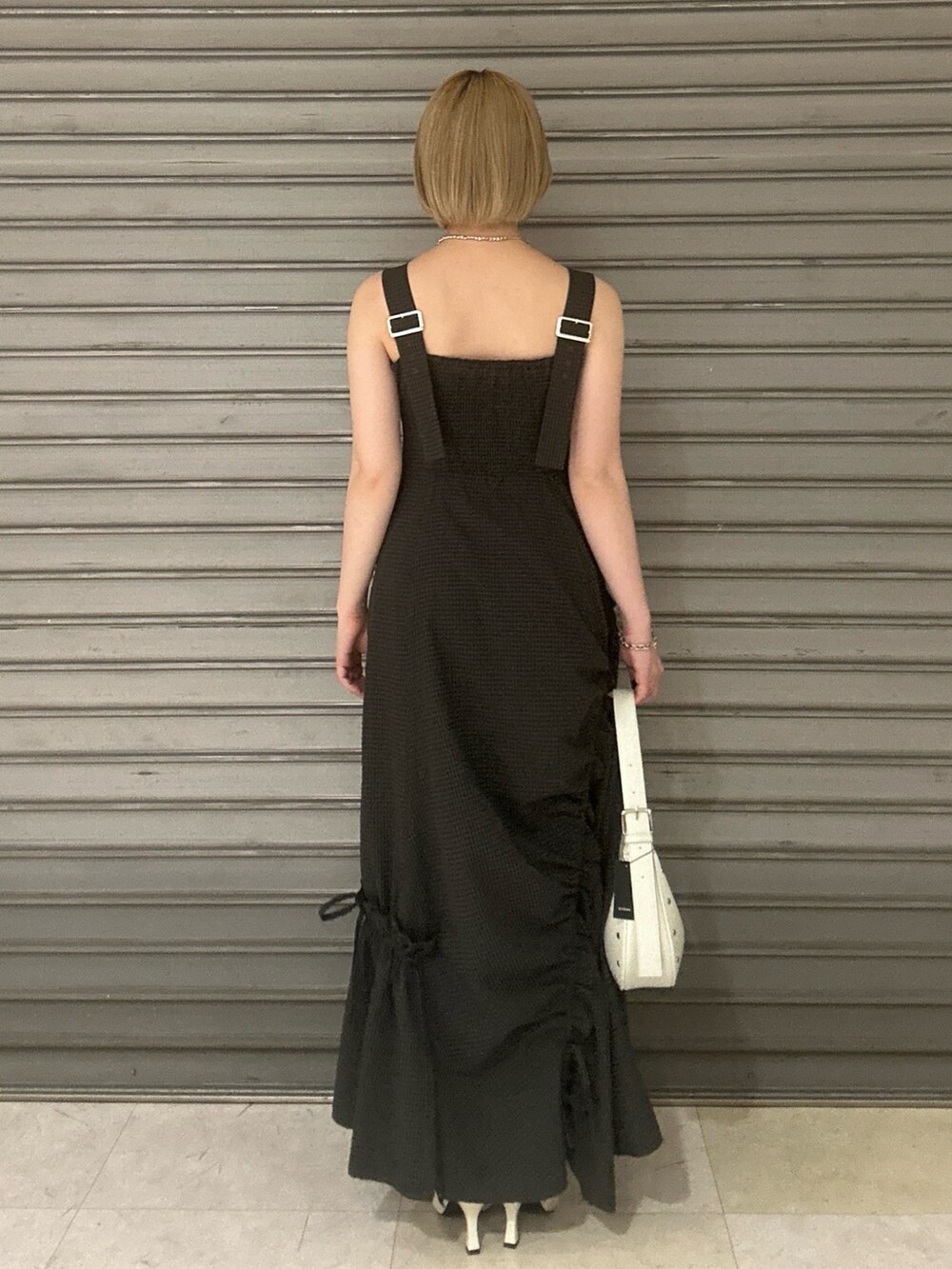 グレー系のワンピース、ホワイト系のハンドバッグ、ホワイト系のパンプスを着用したレディースの春コーディネートの3枚目の写真