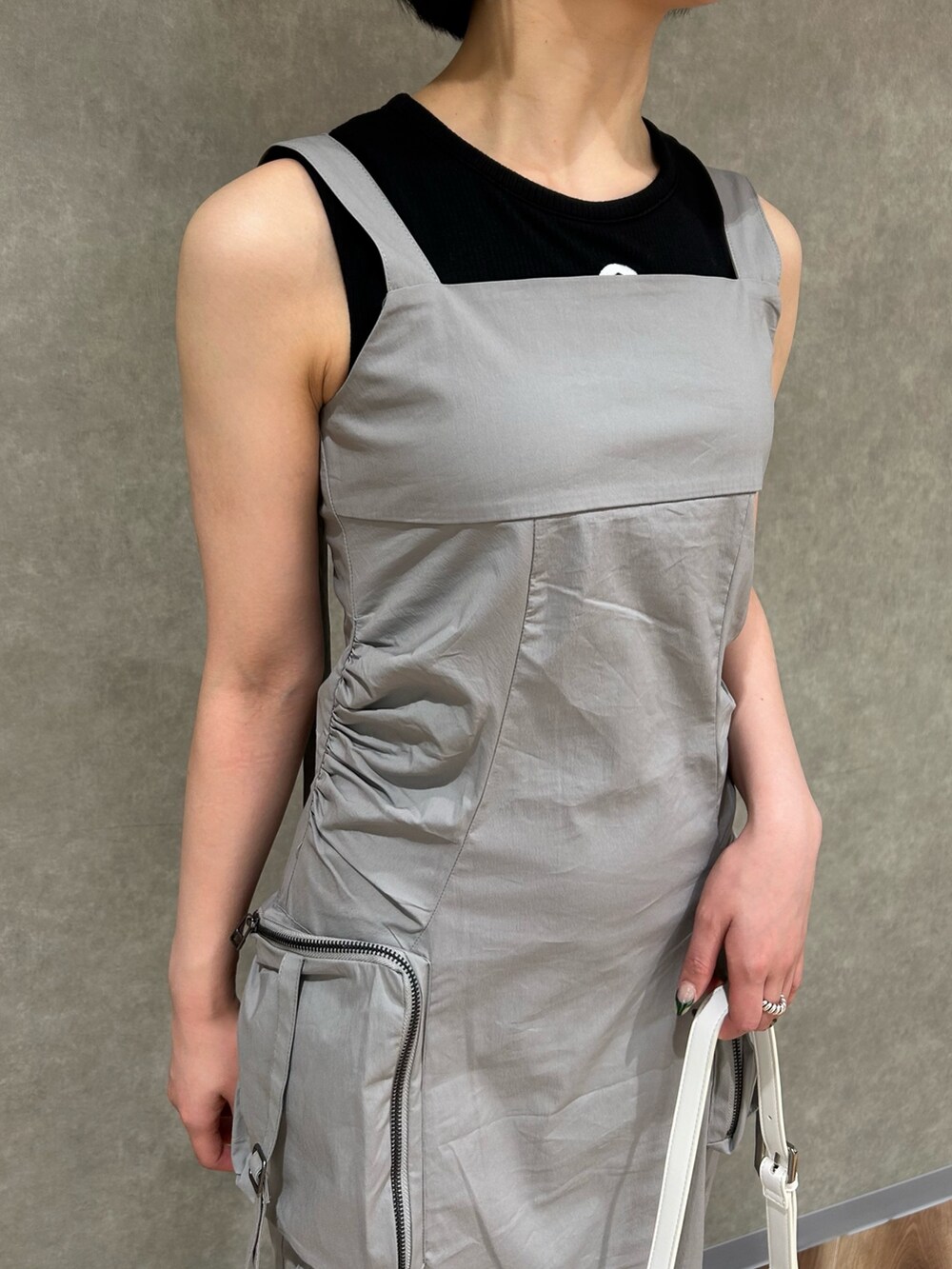 グレー系のワンピース、ブラック系のタンクトップ、ホワイト系のハンドバッグを着用したレディースの夏コーディネートの4枚目の写真