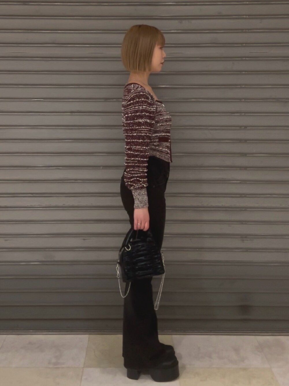 ブラック系のハンドバッグ、レッド系のニット/セーター、ブラック系のデニムパンツを着用したレディースの冬コーディネートの2枚目の写真