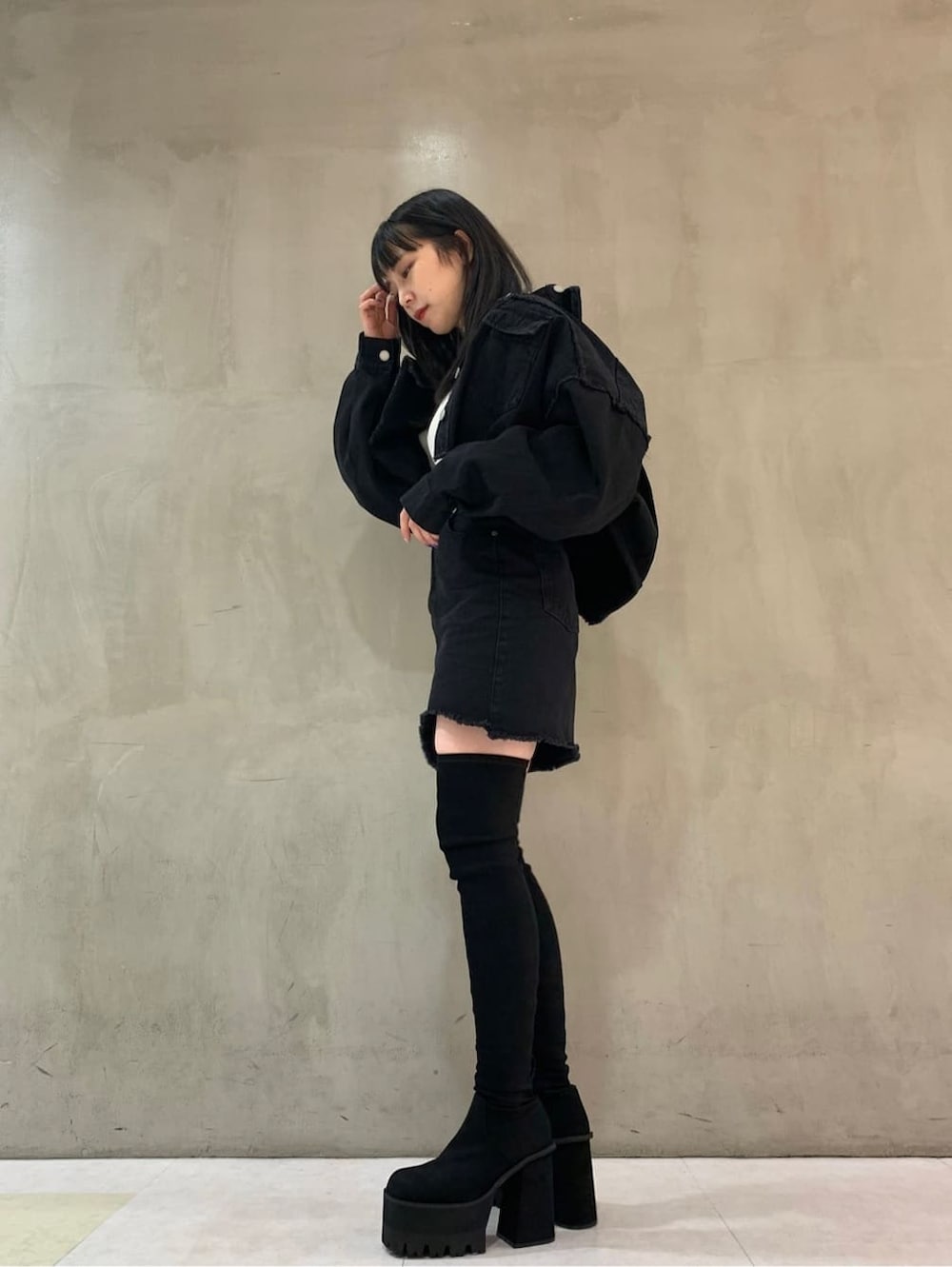 ブラック系のブーツ、ブラック系のデニムジャケット、ホワイト系のニット/セーターを着用したレディースの夏コーディネートの2枚目の写真