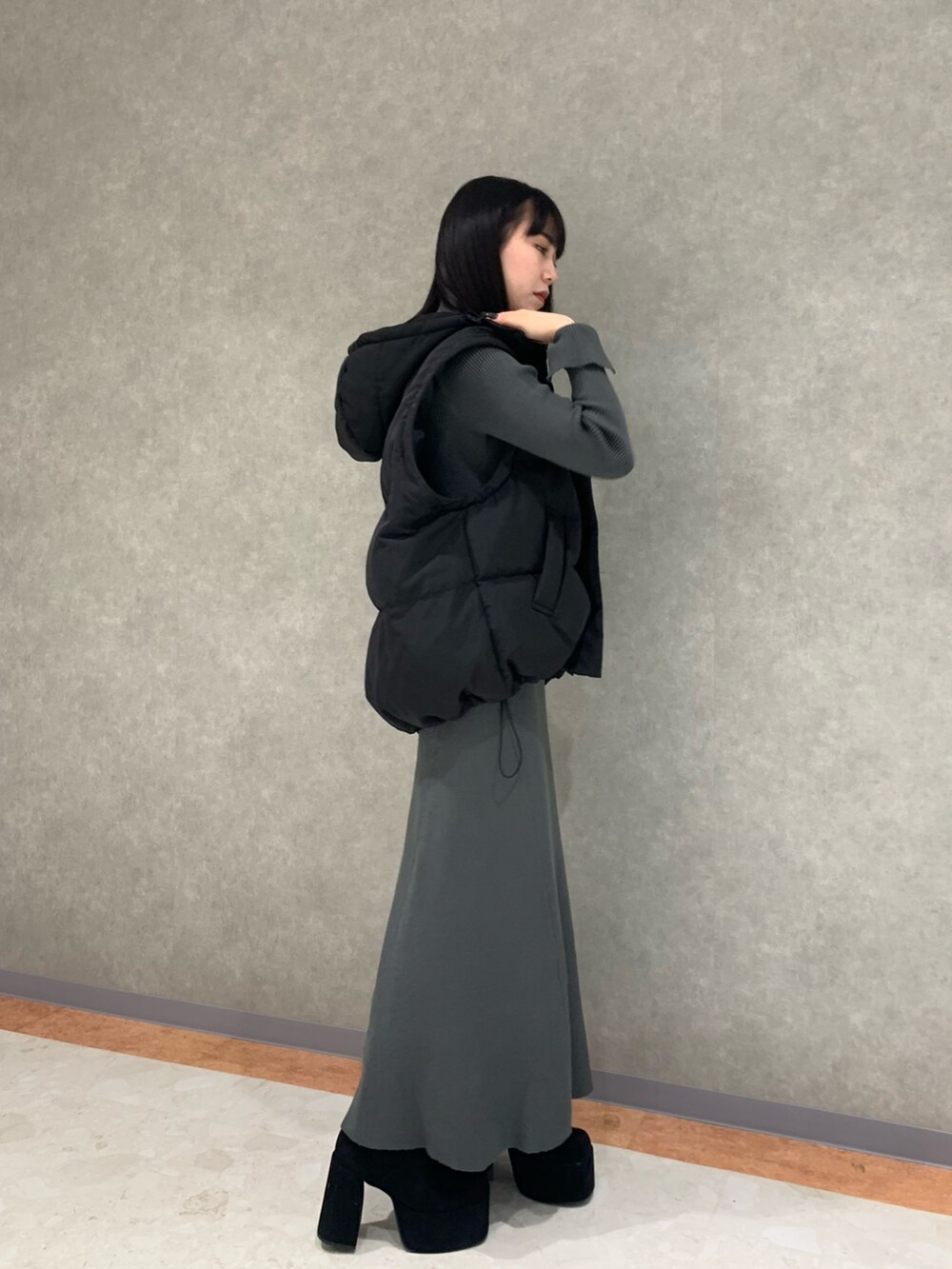 グレー系のワンピース、ブラック系のダウンジャケット/コート、ブラック系のブーツを着用したレディースの冬コーディネートの5枚目の写真