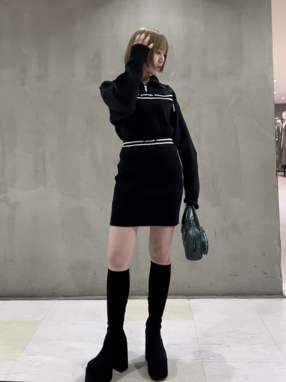 ホワイト系のダウンベスト、ブルー系のニット/セーター、ブルー系のスカートを着用したレディースの秋コーディネートの4枚目の写真