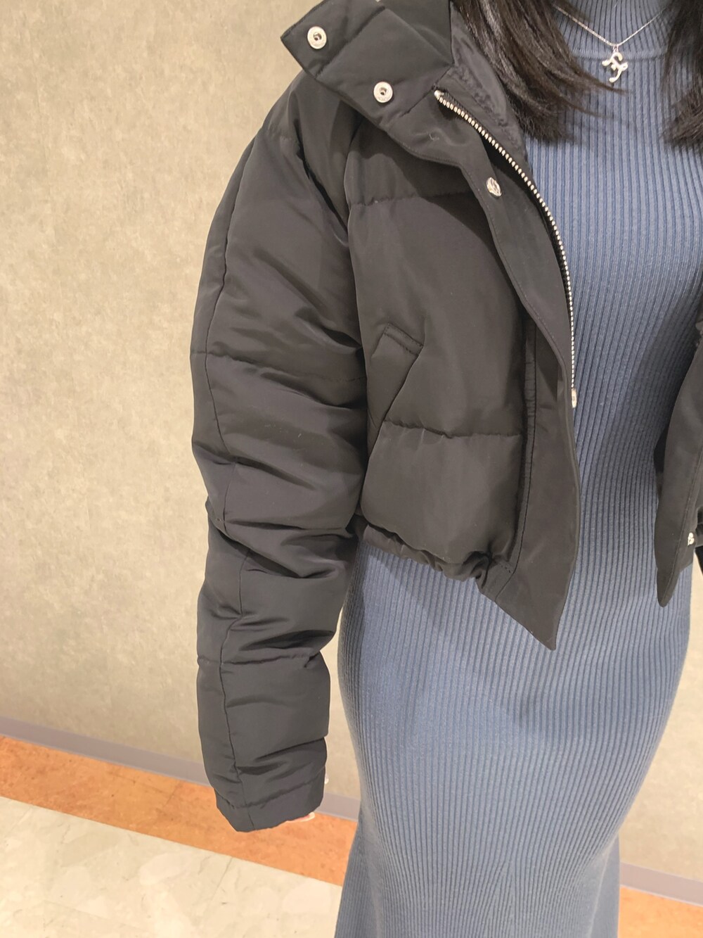 ブルー系のワンピース、ブラック系のダウンジャケット/コート、ブラック系のブーツを着用したレディースの冬コーディネートの7枚目の写真