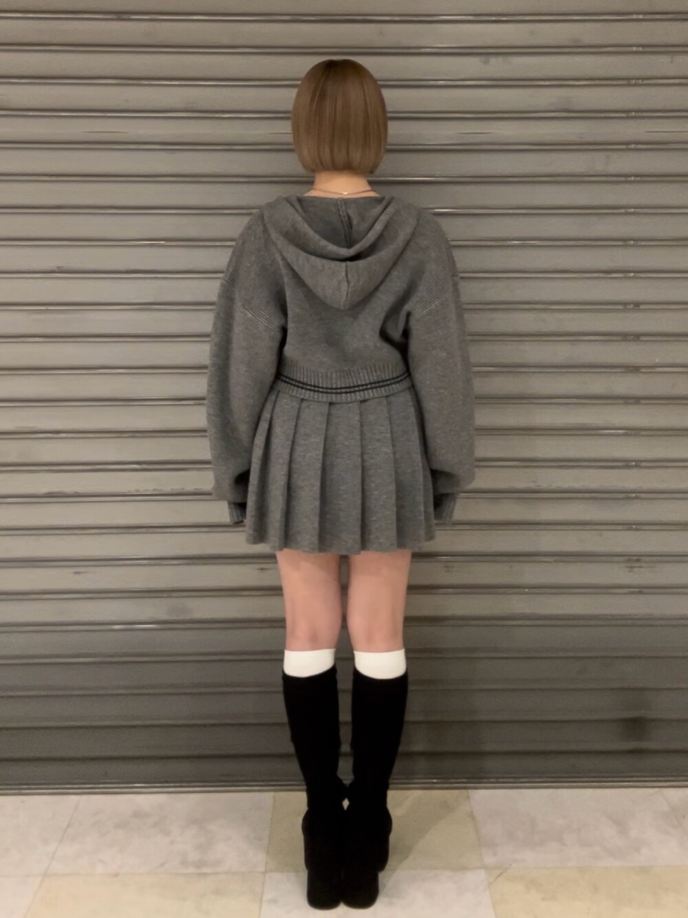 グレー系のニット/セーター、グレー系のスカート、その他のブーツを着用したレディースの秋コーディネートの4枚目の写真