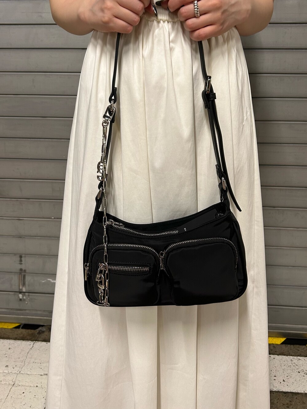 ホワイト系のワンピース、ブラック系のハンドバッグ、ブラック系のサンダルを着用したレディースの夏コーディネートの5枚目の写真