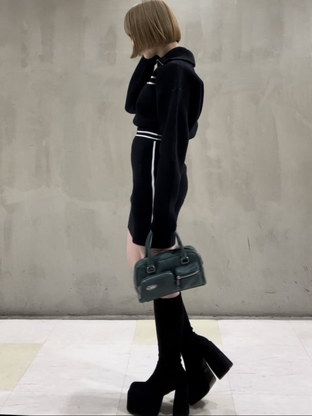 ホワイト系のダウンベスト、ブルー系のニット/セーター、ブルー系のスカートを着用したレディースの秋コーディネートの5枚目の写真