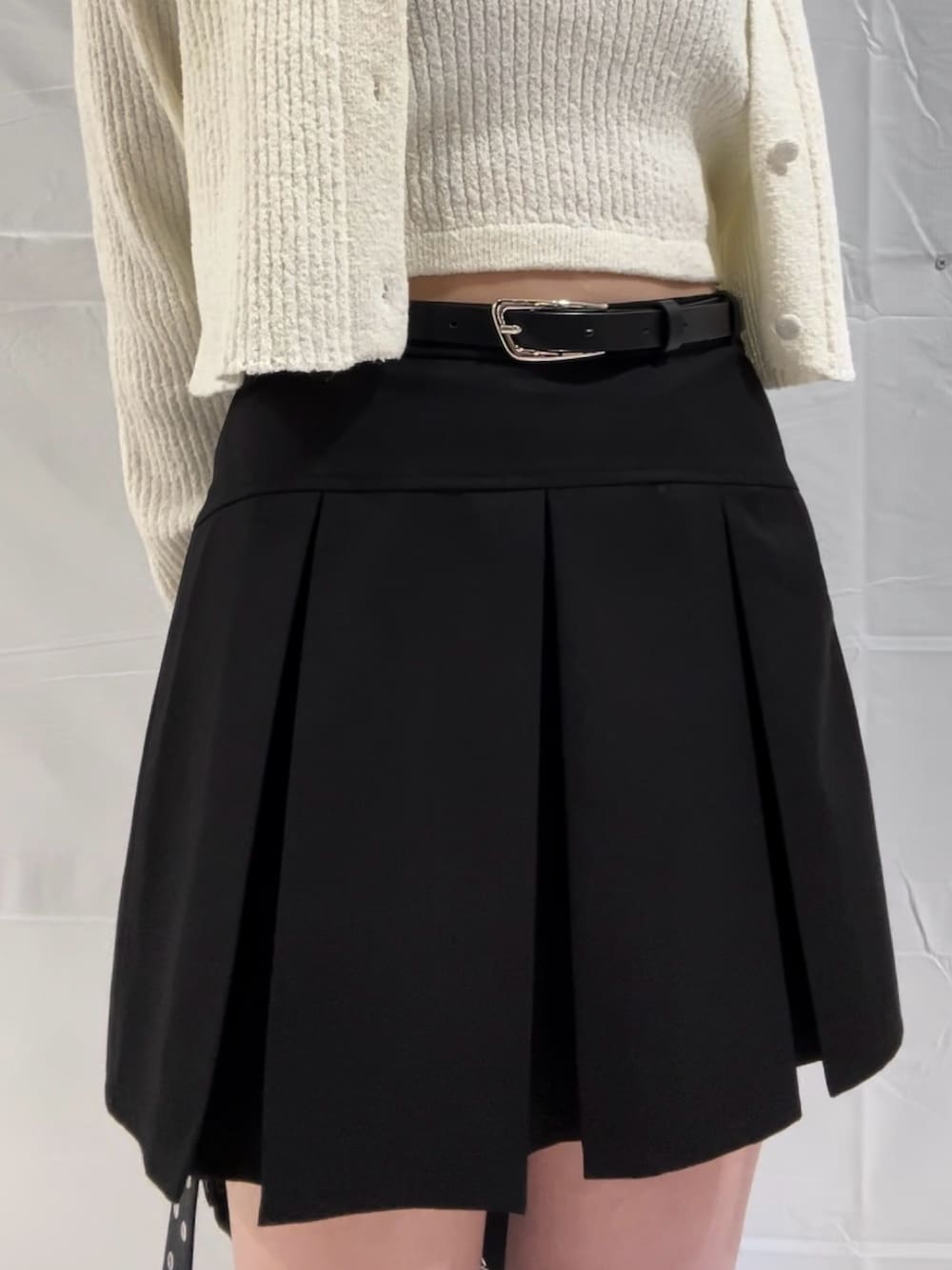 ホワイト系のニット/セーター、ブラック系のスカート、ブラック系のサンダルを着用したレディースの春コーディネートの5枚目の写真