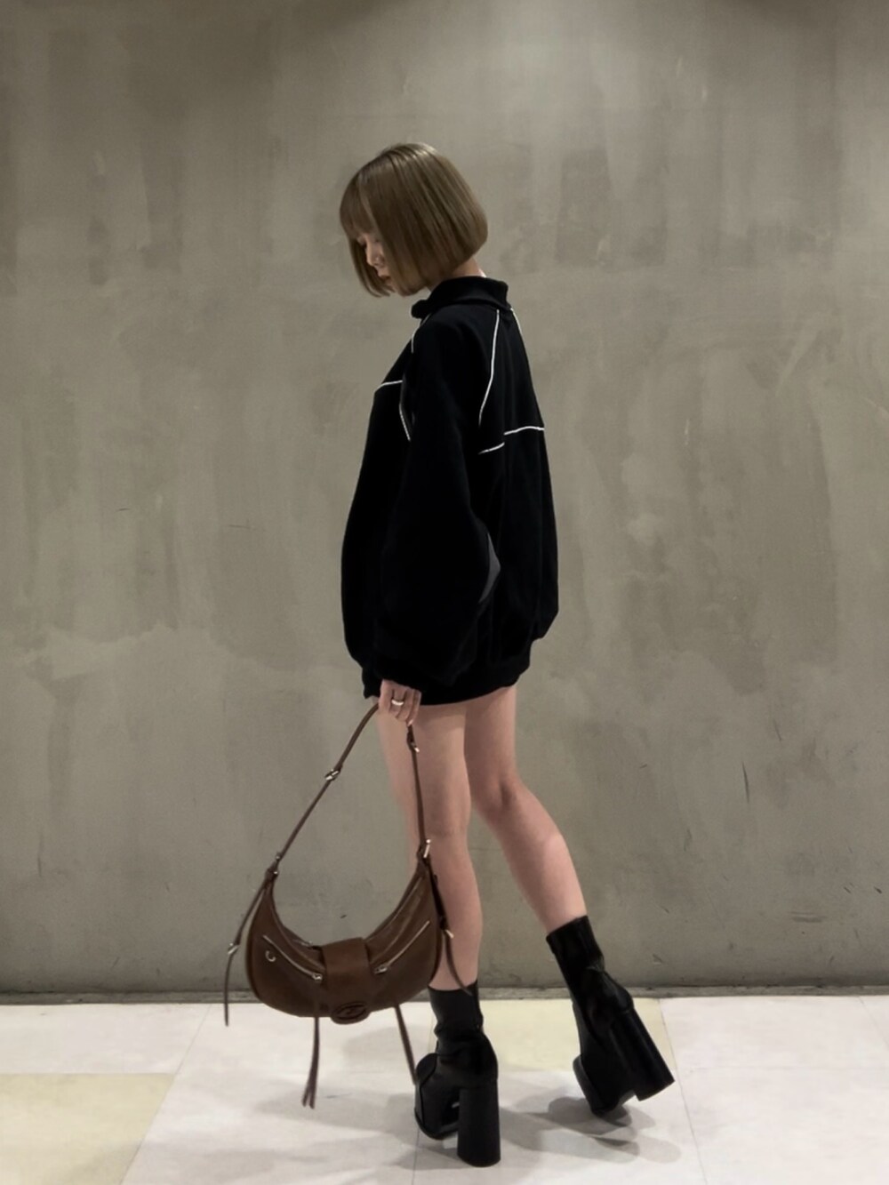 ブラック系のTシャツ/カットソー、ブラック系のスカート、ブラウン系のハンドバッグを着用したレディースの冬コーディネートの3枚目の写真