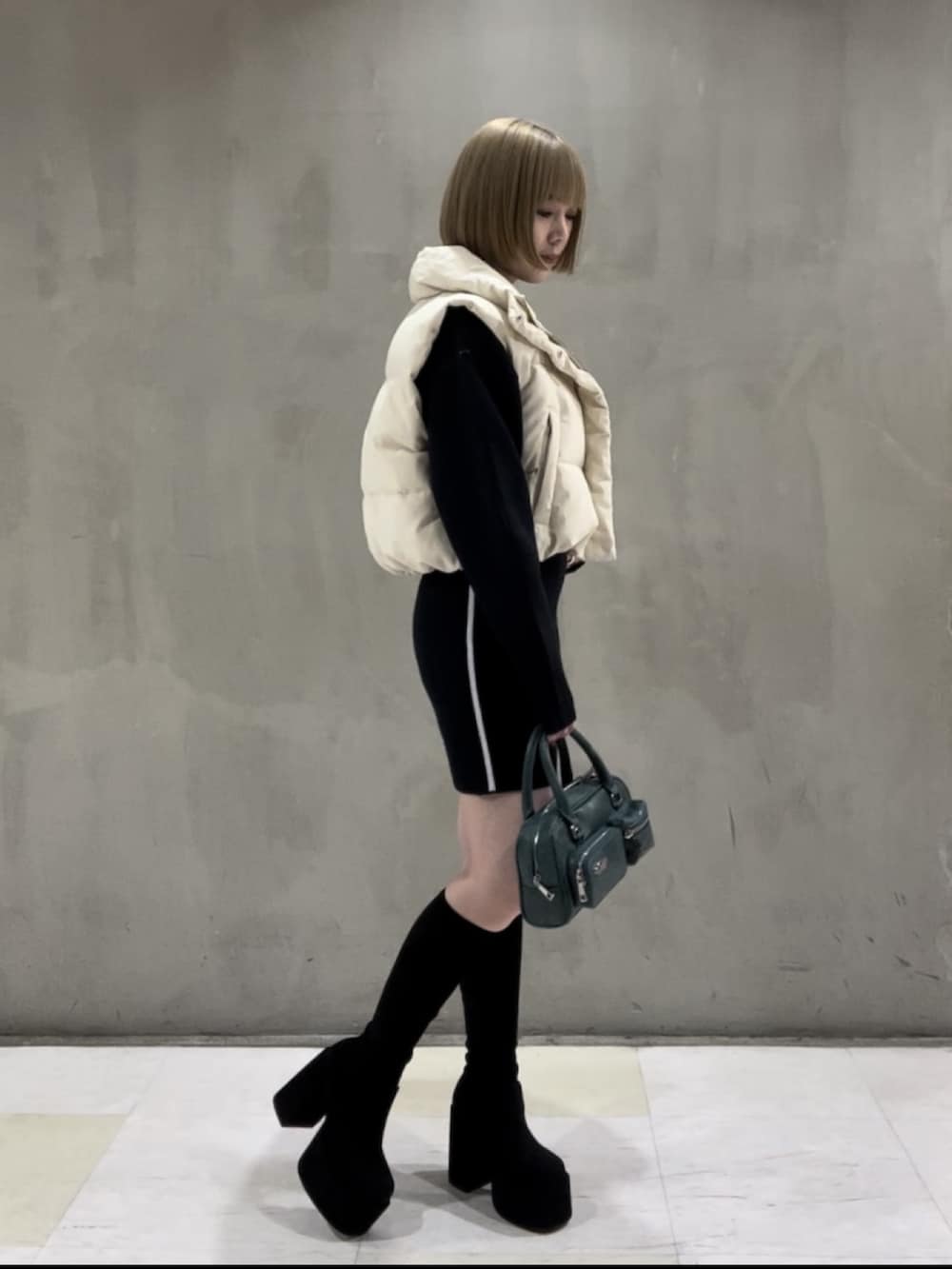 ホワイト系のダウンベスト、ブルー系のニット/セーター、ブルー系のスカートを着用したレディースの秋コーディネートの2枚目の写真