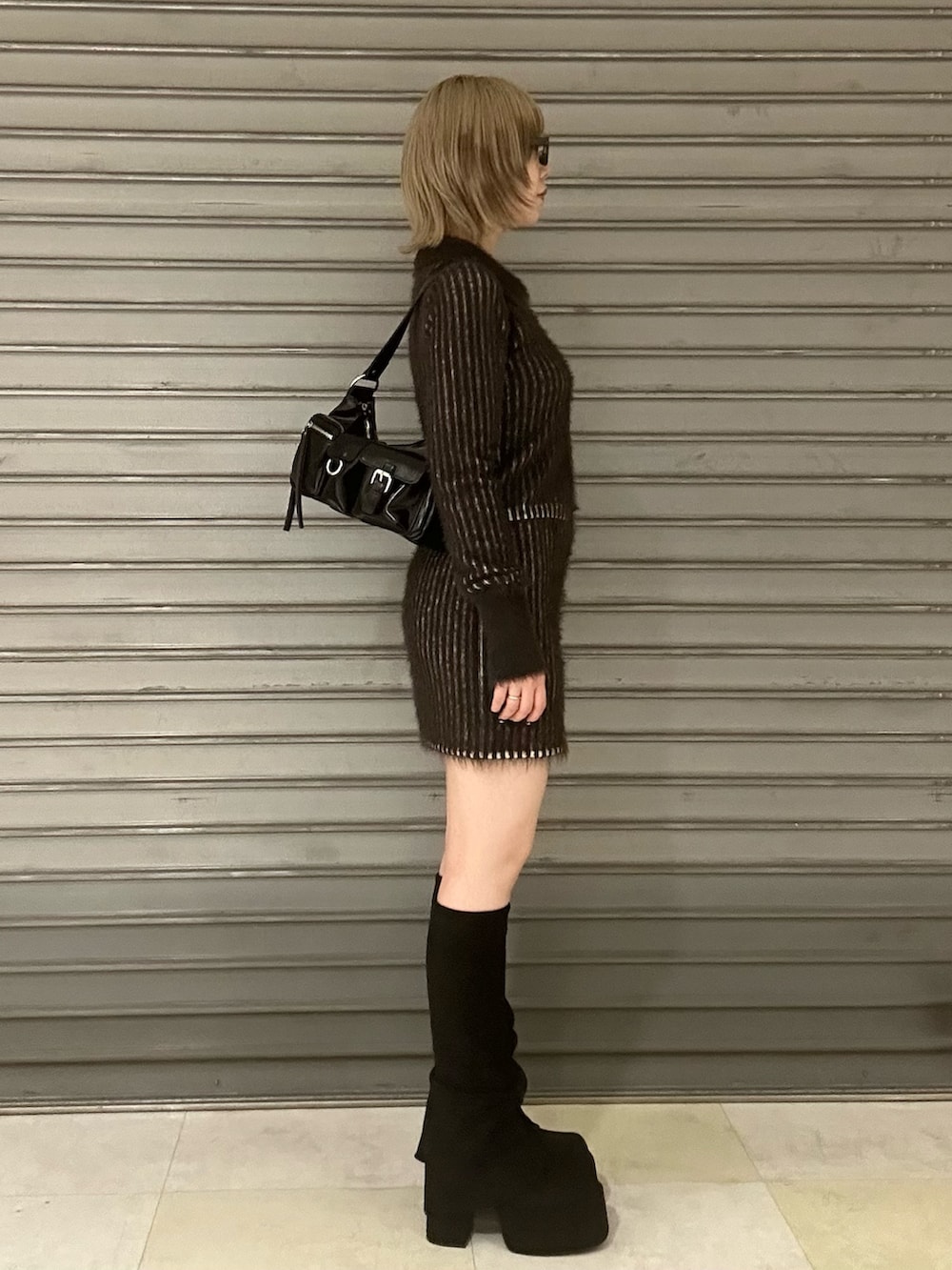 ブラウン系のニット/セーター、ブラウン系のスカート、ブラック系のブーツを着用したレディースの秋コーディネートの2枚目の写真