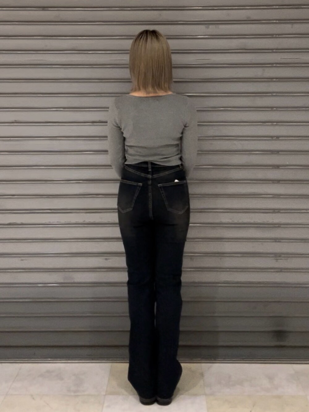 ブルー系のデニムパンツ、グレー系のニット/セーター、ブラック系のブーツを着用したレディースの秋コーディネートの6枚目の写真