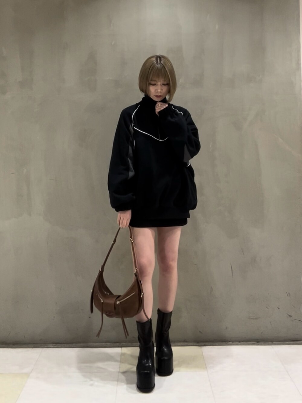 ブラック系のTシャツ/カットソー、ブラック系のスカート、ブラウン系のハンドバッグを着用したレディースの冬コーディネートの2枚目の写真