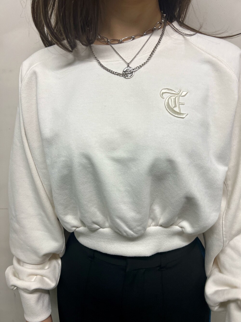 ブラック系のスラックス、ブラック系のショルダーバッグ、ホワイト系のスウェットを着用したレディースの冬コーディネートの5枚目の写真