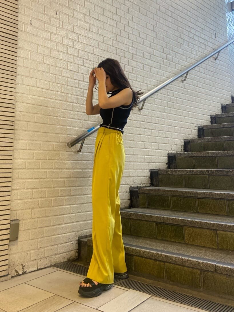 イエロー系のスラックス、ブラック系のショルダーバッグ、ブラック系のサンダルを着用したレディースの春コーディネートの3枚目の写真