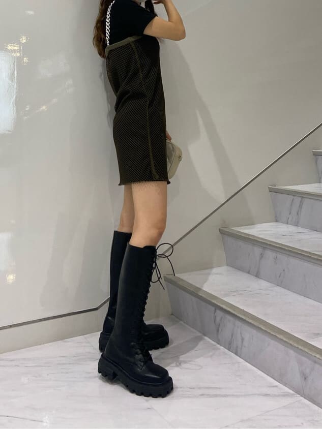 ブラック系のブーツ、ホワイト系のショルダーバッグ、ブラック系のワンピースを着用したレディースの夏コーディネートの3枚目の写真