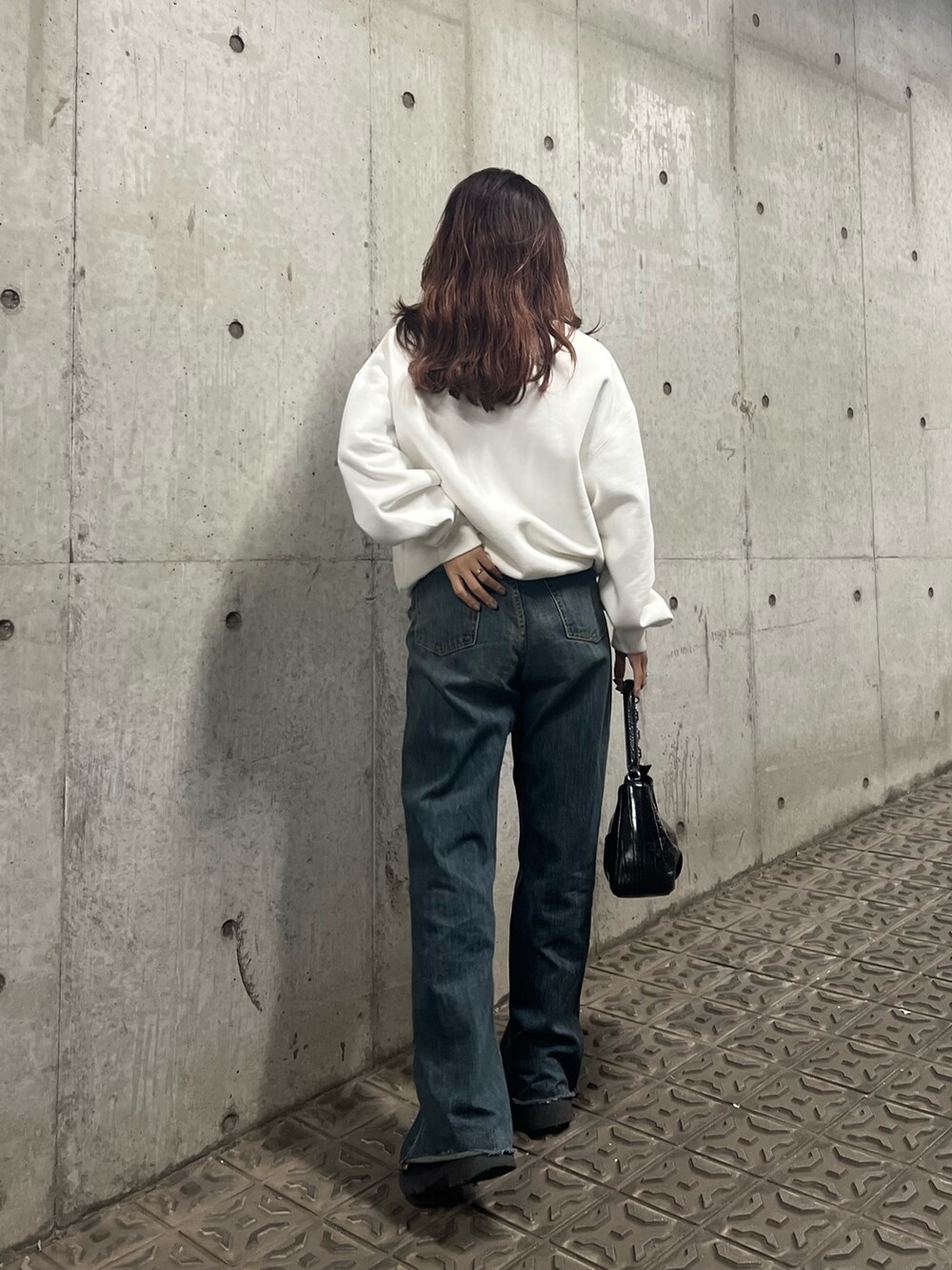 ブルー系のデニムパンツ、ブラック系のブーツ、ブラック系のハンドバッグを着用したレディースの冬コーディネートの5枚目の写真