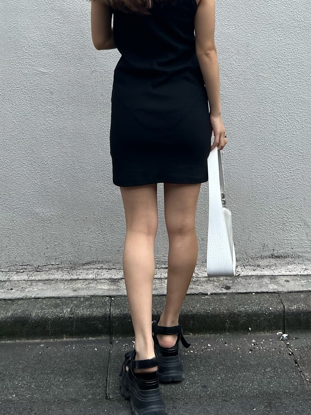 ブラック系のワンピース、ブラック系のサンダル、ホワイト系のハンドバッグを着用したレディースの夏コーディネートの8枚目の写真