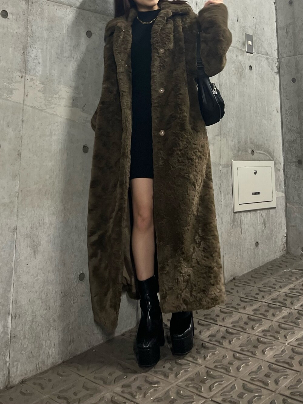 ブラック系のブーツ、ブラウン系のチェスターコート、ブラック系のワンピースを着用したレディースの冬コーディネートの3枚目の写真