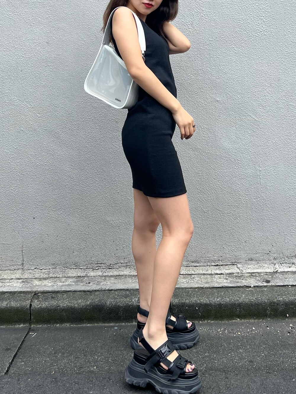ブラック系のワンピース、ブラック系のサンダル、ホワイト系のハンドバッグを着用したレディースの夏コーディネートの5枚目の写真