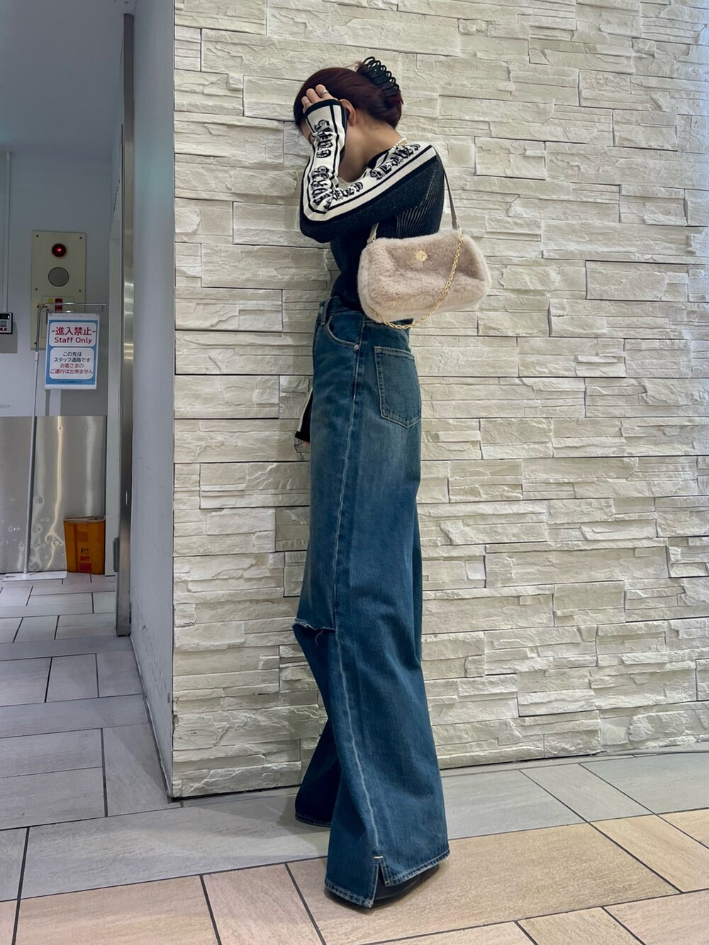 ブルー系のデニムパンツ、ホワイト系のショルダーバッグ、ブラック系のニット/セーターを着用したレディースの冬コーディネートの5枚目の写真