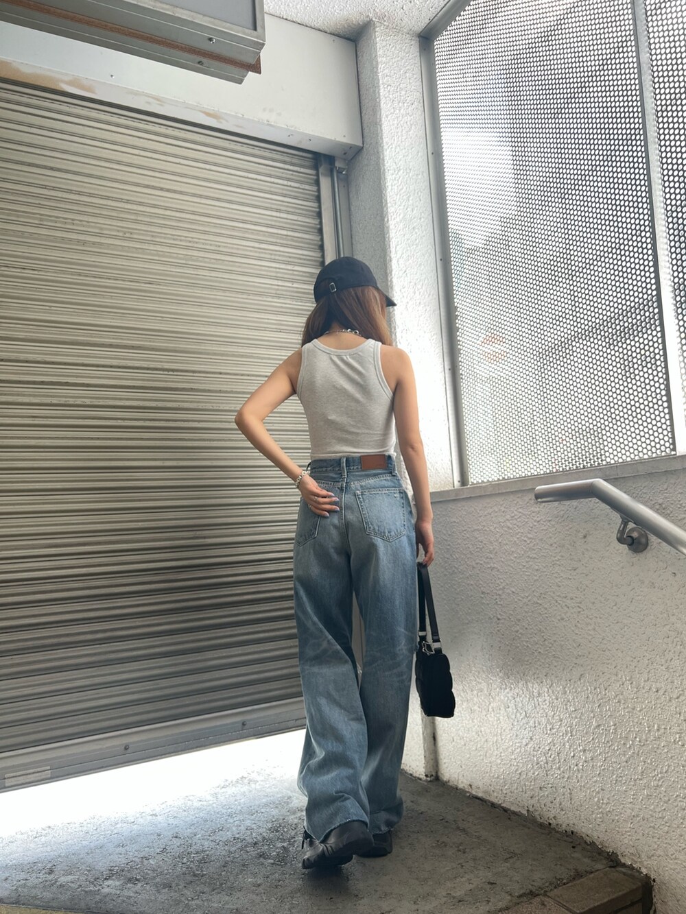 ブラック系のサンダル、ブルー系のデニムパンツ、グレー系のタンクトップを着用したレディースの夏コーディネートの6枚目の写真