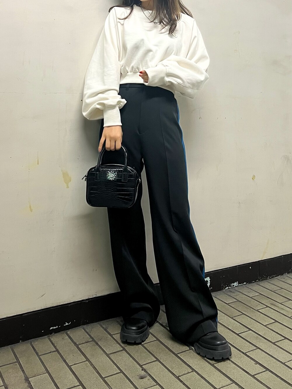 ブラック系のスラックス、ブラック系のショルダーバッグ、ホワイト系のスウェットを着用したレディースの冬コーディネートの2枚目の写真