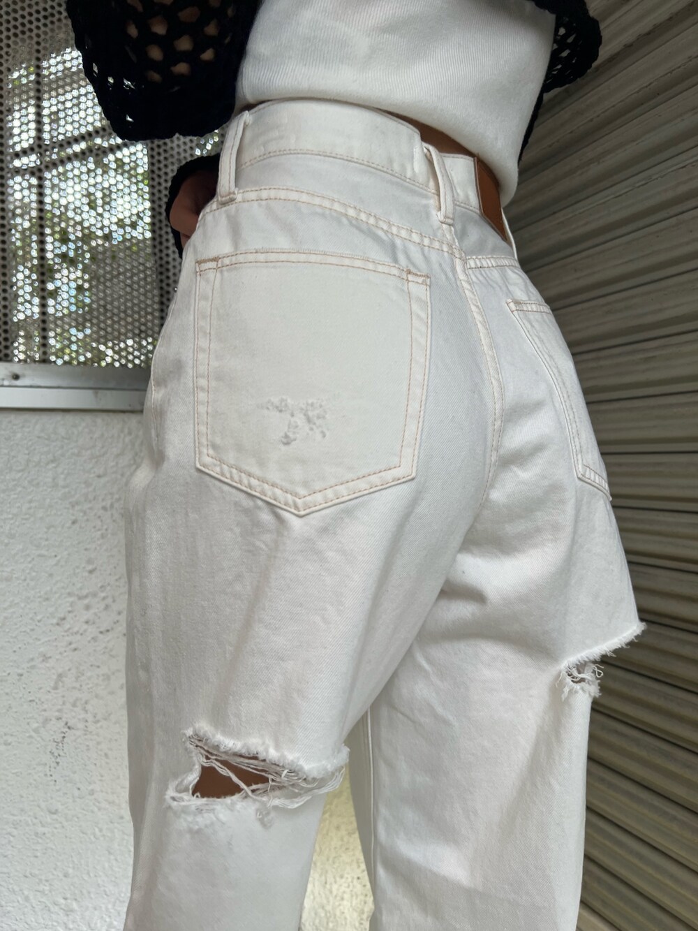 ホワイト系のデニムパンツ、ブラック系のサンダル、ブラック系のニット/セーターを着用したレディースの春コーディネートの7枚目の写真