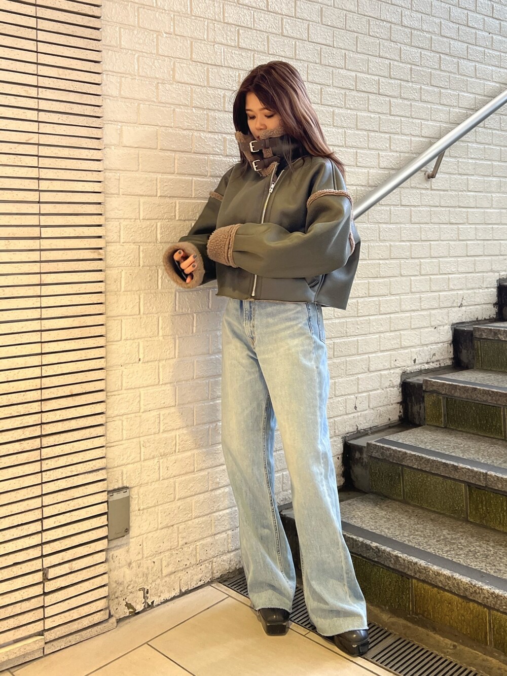 ベージュ系のブルゾン、ブルー系のデニムパンツ、ブラック系のブーツを着用したレディースの冬コーディネートの2枚目の写真