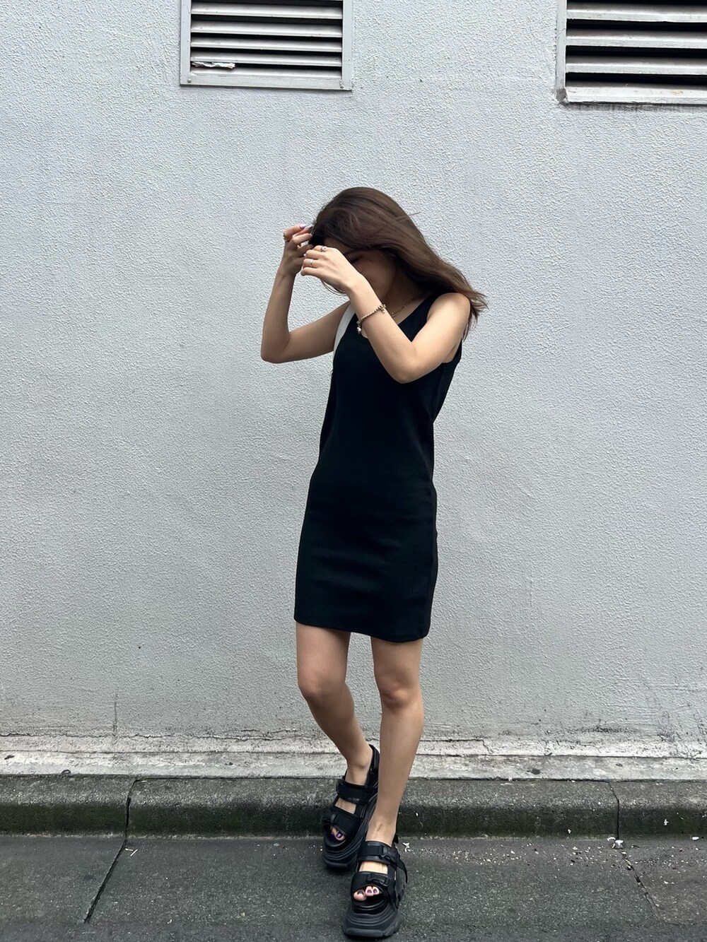 ブラック系のワンピース、ブラック系のサンダル、ホワイト系のハンドバッグを着用したレディースの夏コーディネートの4枚目の写真