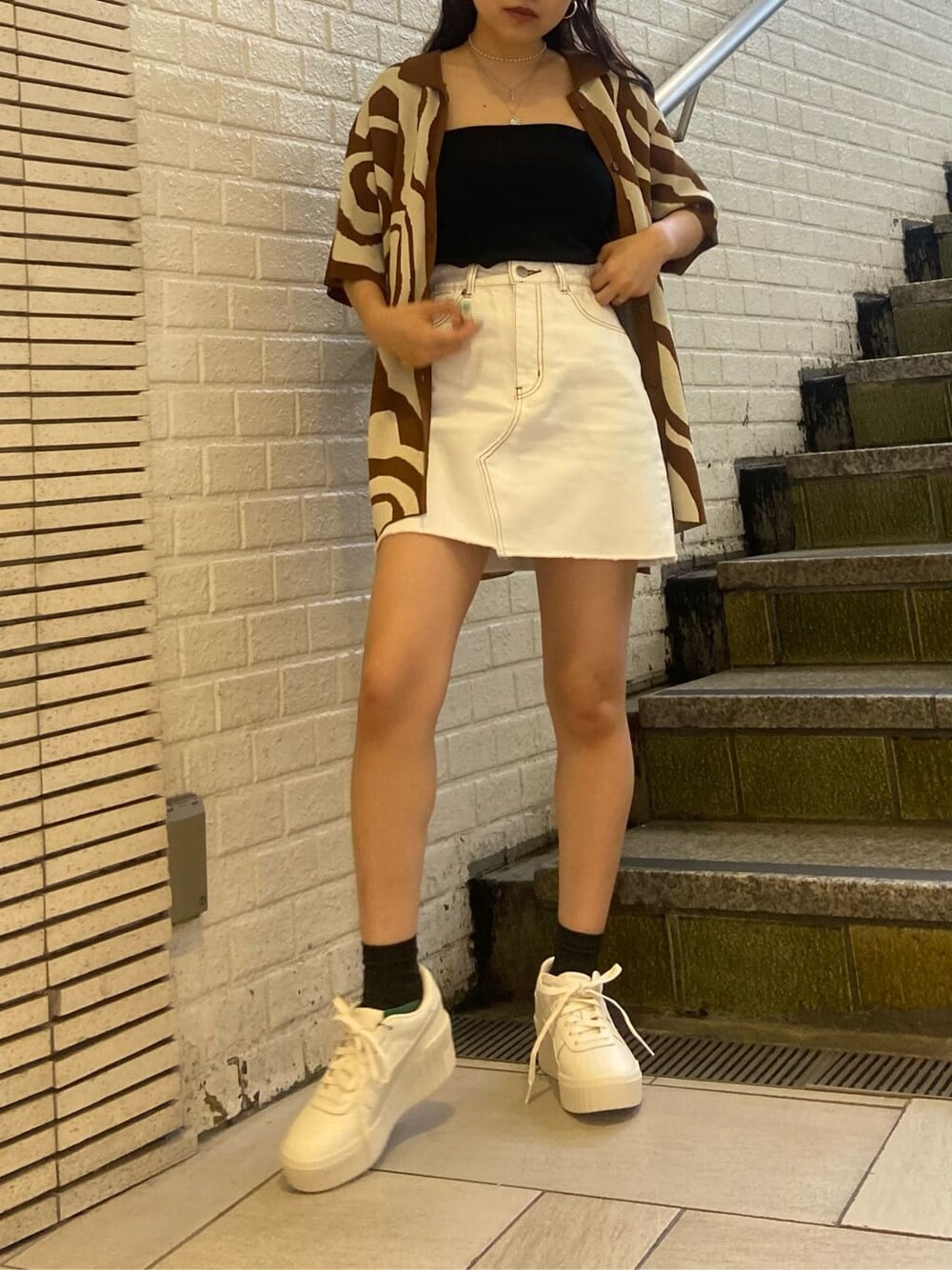 ホワイト系のスニーカー、ブラック系のキャミソール、ブラウン系のニット/セーターを着用したレディースの春コーディネートの2枚目の写真