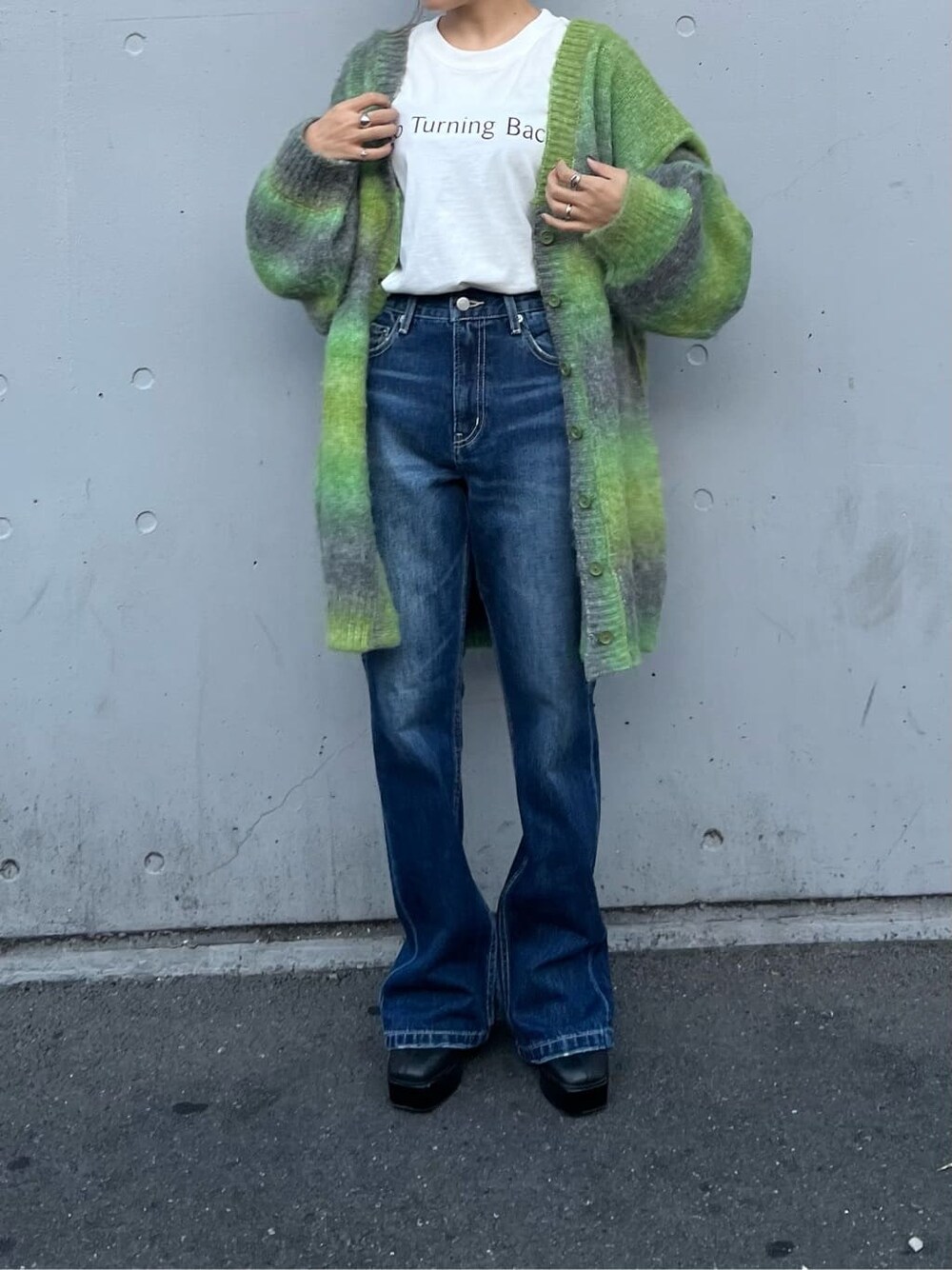 ブラック系のブーツ、ホワイト系のTシャツ/カットソー、ブルー系のデニムパンツを着用したレディースの秋コーディネートの3枚目の写真
