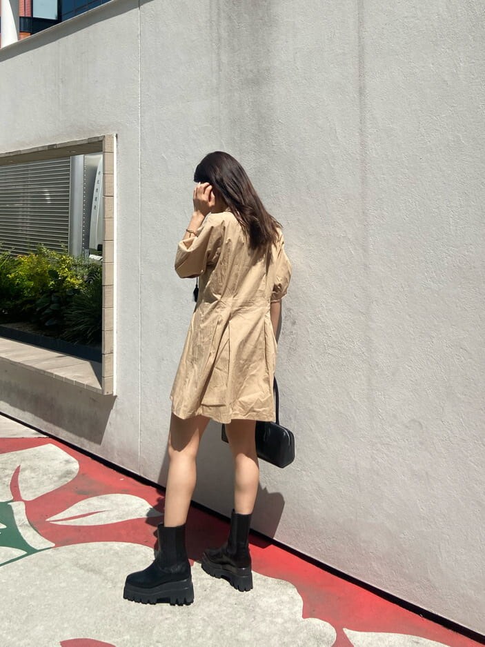 ブラック系のボストンバッグ、ブラック系のブーツ、ベージュ系のワンピースを着用したレディースの春コーディネートの4枚目の写真