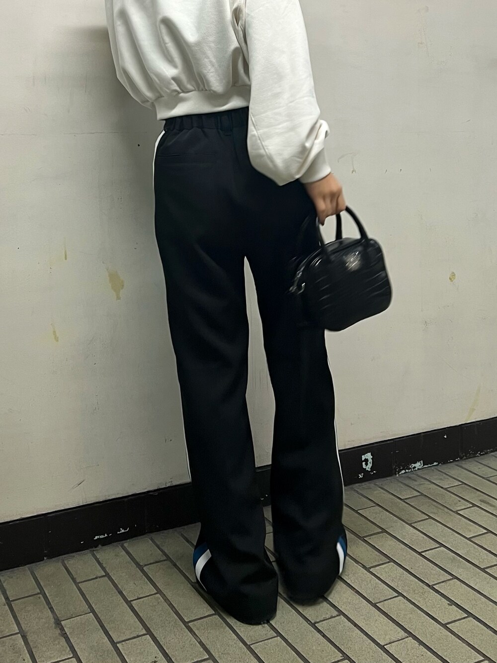 ブラック系のスラックス、ブラック系のショルダーバッグ、ホワイト系のスウェットを着用したレディースの冬コーディネートの4枚目の写真