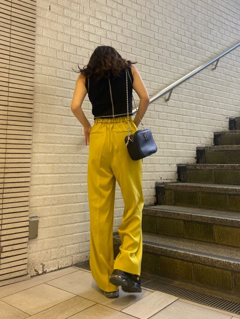 イエロー系のスラックス、ブラック系のショルダーバッグ、ブラック系のサンダルを着用したレディースの春コーディネートの4枚目の写真