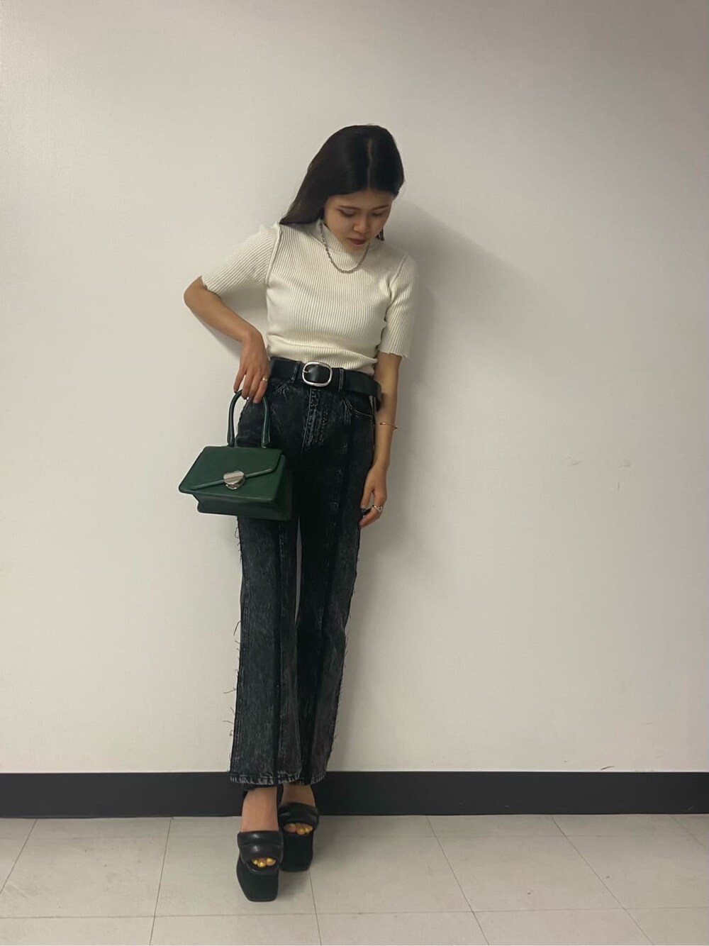 グリーン系のハンドバッグ、ブラック系のデニムパンツ、ホワイト系のニット/セーターを着用したレディースの夏コーディネートの2枚目の写真