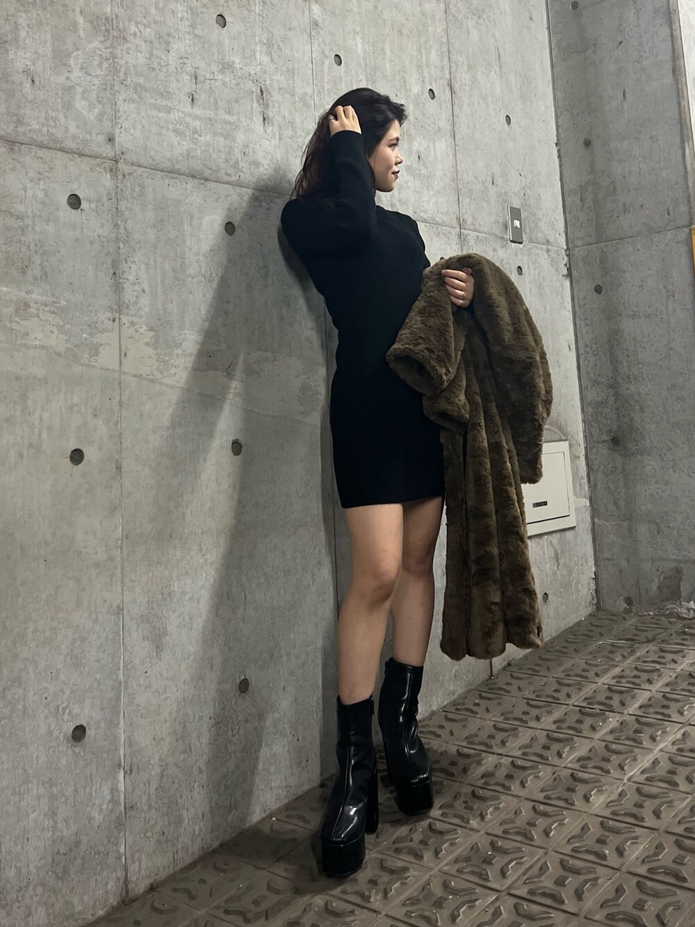 ブラック系のブーツ、ブラウン系のチェスターコート、ブラック系のワンピースを着用したレディースの冬コーディネートの6枚目の写真