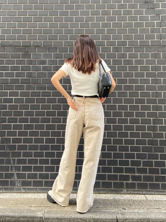 ブラック系のボストンバッグ、ベージュ系のTシャツ/カットソー、ベージュ系のデニムパンツを着用したレディースの春コーディネートの4枚目の写真