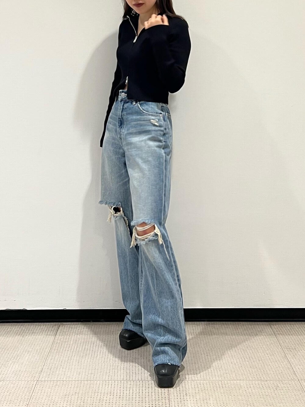 ブルー系のデニムパンツ、ブラック系のニット/セーター、ブラック系のブーツを着用したレディースの秋コーディネートの2枚目の写真