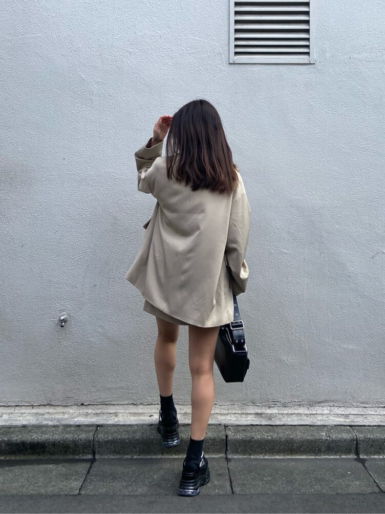 ブラック系のショルダーバッグ、ブラック系のTシャツ/カットソー、ベージュ系のスカートを着用したレディースの春コーディネートの2枚目の写真