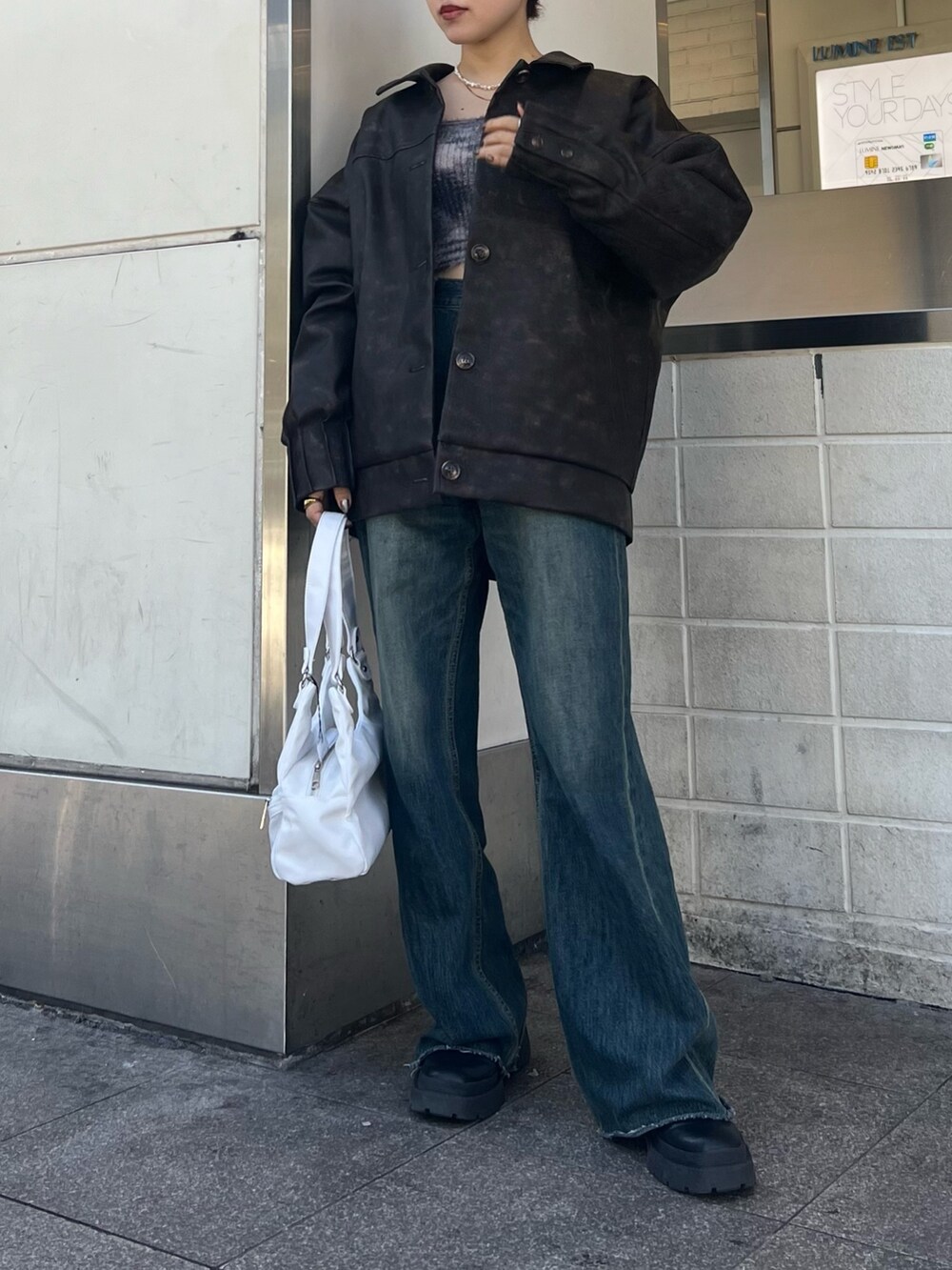 ブルー系のデニムパンツ、ホワイト系のハンドバッグ、ブラック系のブーツを着用したレディースの冬コーディネートの2枚目の写真