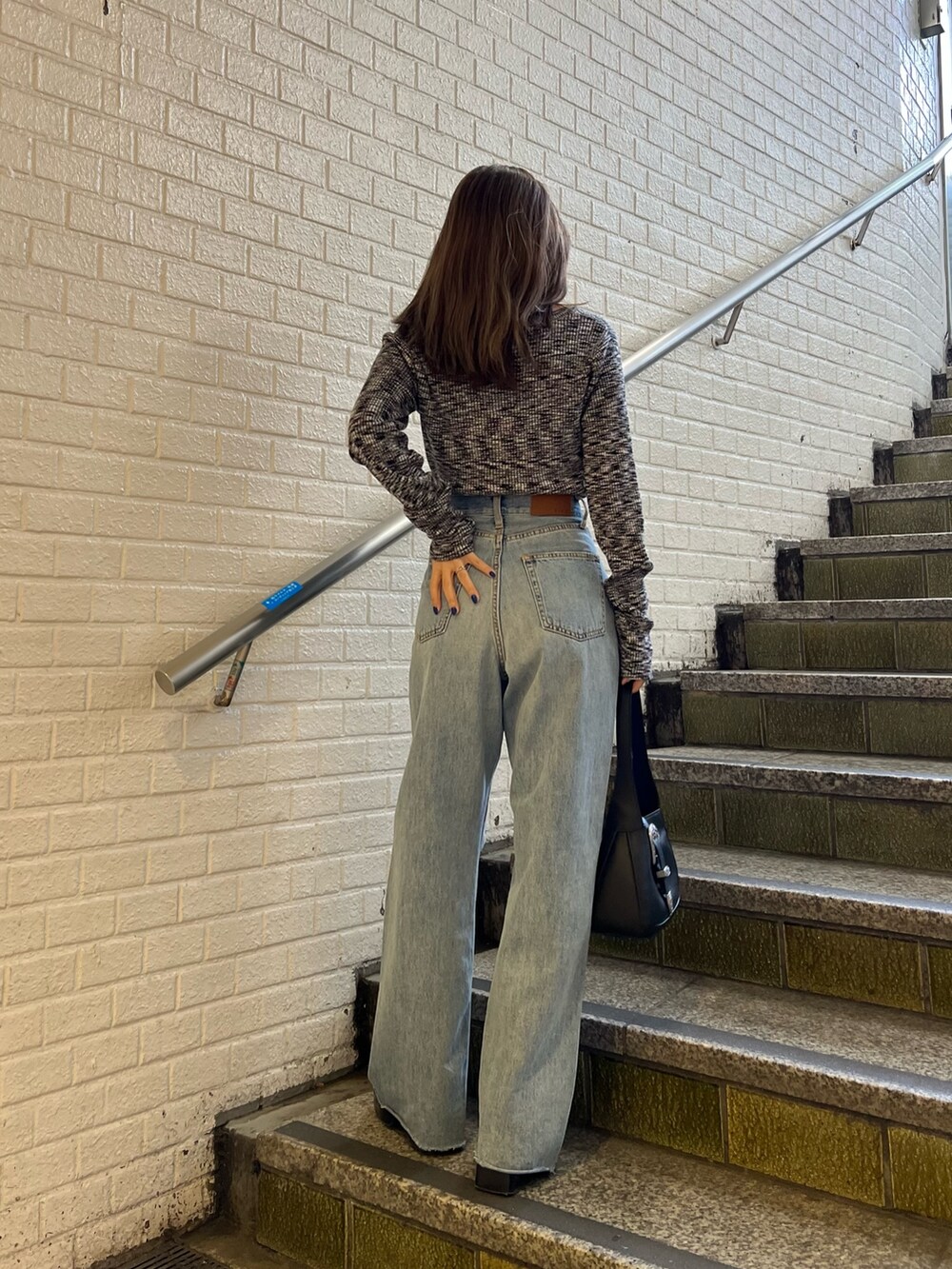 ブルー系のデニムパンツ、ブラック系のハンドバッグ、ブラック系のニット/セーターを着用したレディースの冬コーディネートの3枚目の写真