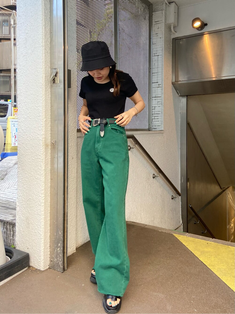 ブラック系のTシャツ/カットソー、グリーン系のデニムパンツ、ブラック系のサンダルを着用したレディースの春コーディネートの2枚目の写真