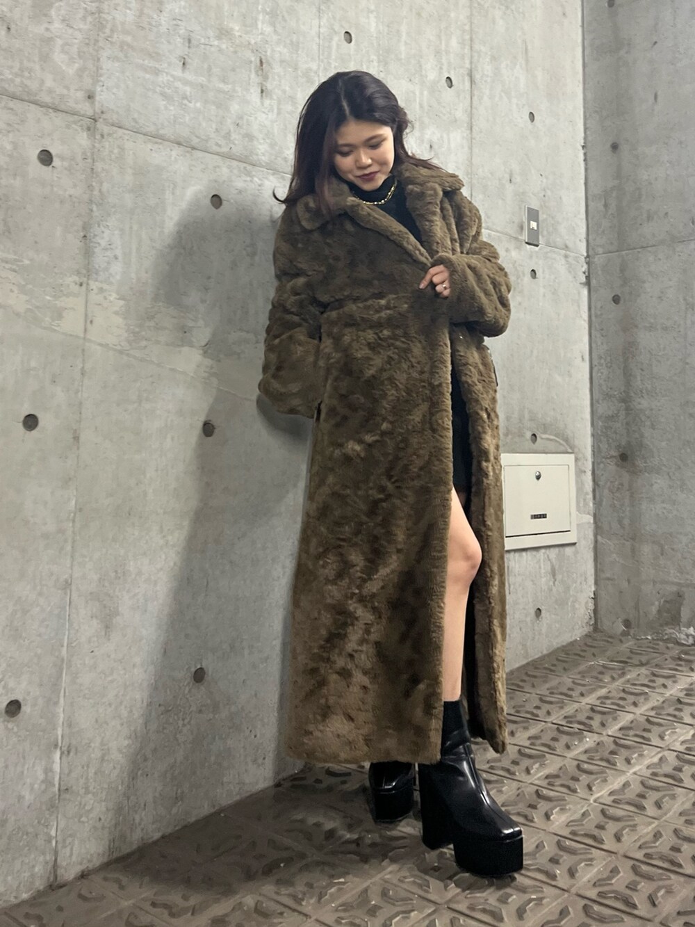 ブラック系のブーツ、ブラウン系のチェスターコート、ブラック系のワンピースを着用したレディースの冬コーディネートの4枚目の写真