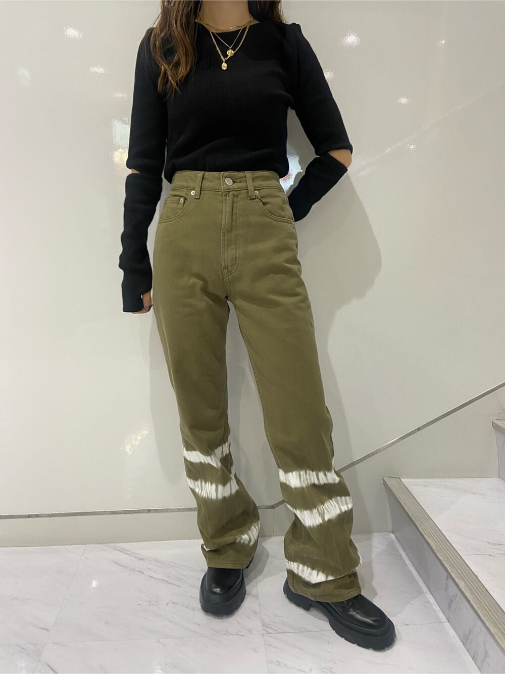 ブラック系のブーツ、ブラック系のTシャツ/カットソー、ベージュ系のデニムパンツを着用したレディースの夏コーディネートの5枚目の写真