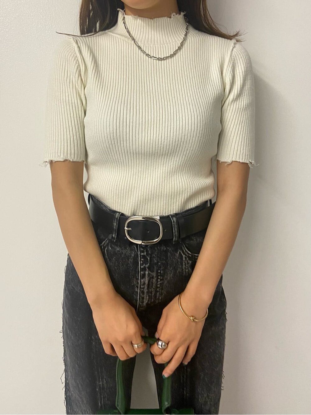 グリーン系のハンドバッグ、ブラック系のデニムパンツ、ホワイト系のニット/セーターを着用したレディースの夏コーディネートの4枚目の写真